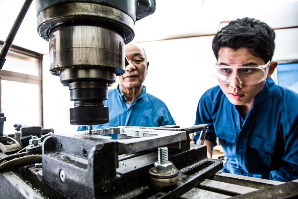 技能実習生に技術指導を行うベテラン社員(製造業)